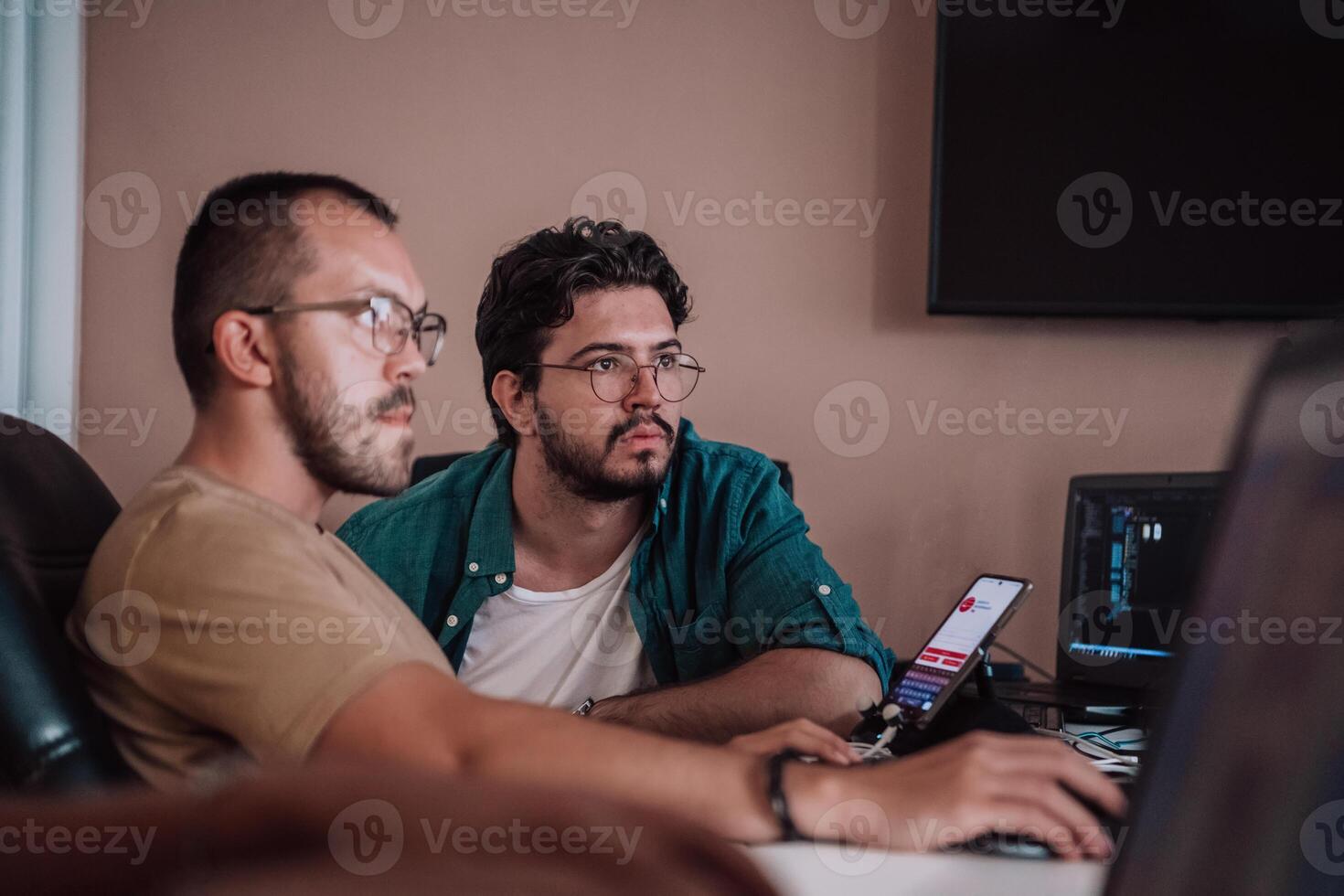 Programmers engrossed in deep collaboration, diligently working together to solve complex problems and develop innovative mobile applications with seamless functionality. photo