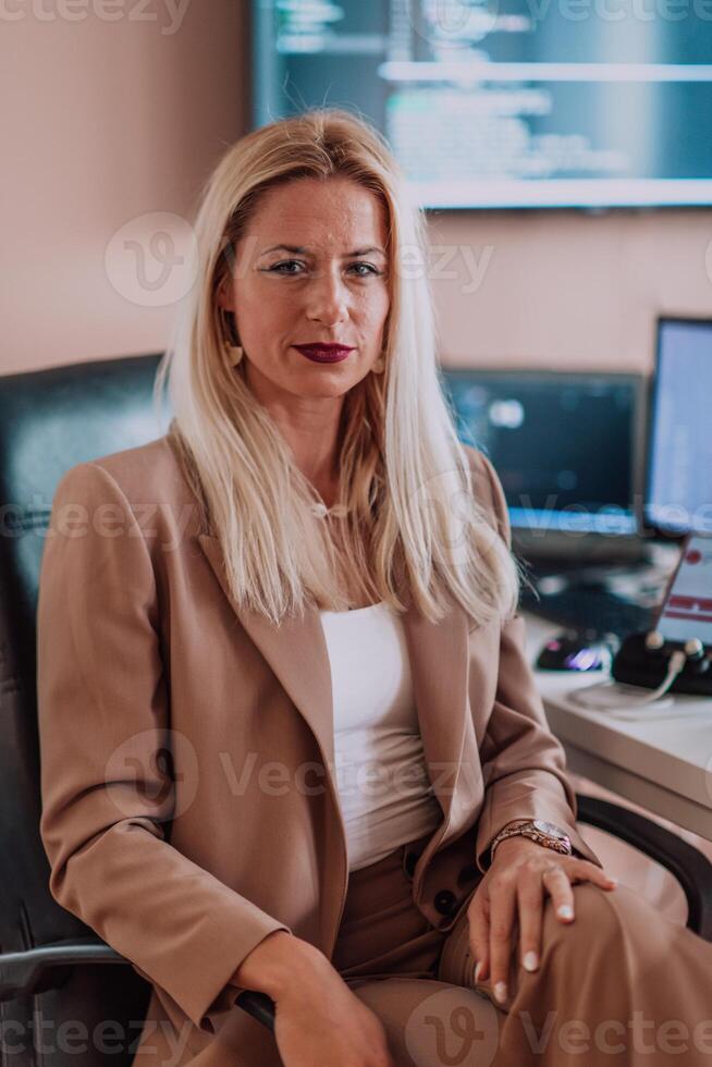 A businesswoman sitting in a programmer's office surrounded by computers, showing her expertise and dedication to technology. photo