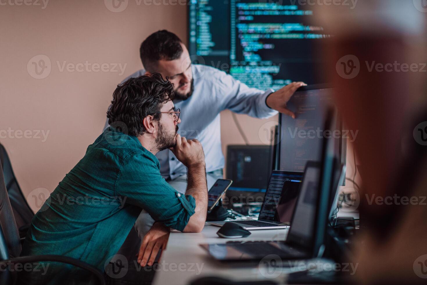 Programmers engrossed in deep collaboration, diligently working together to solve complex problems and develop innovative mobile applications with seamless functionality. photo