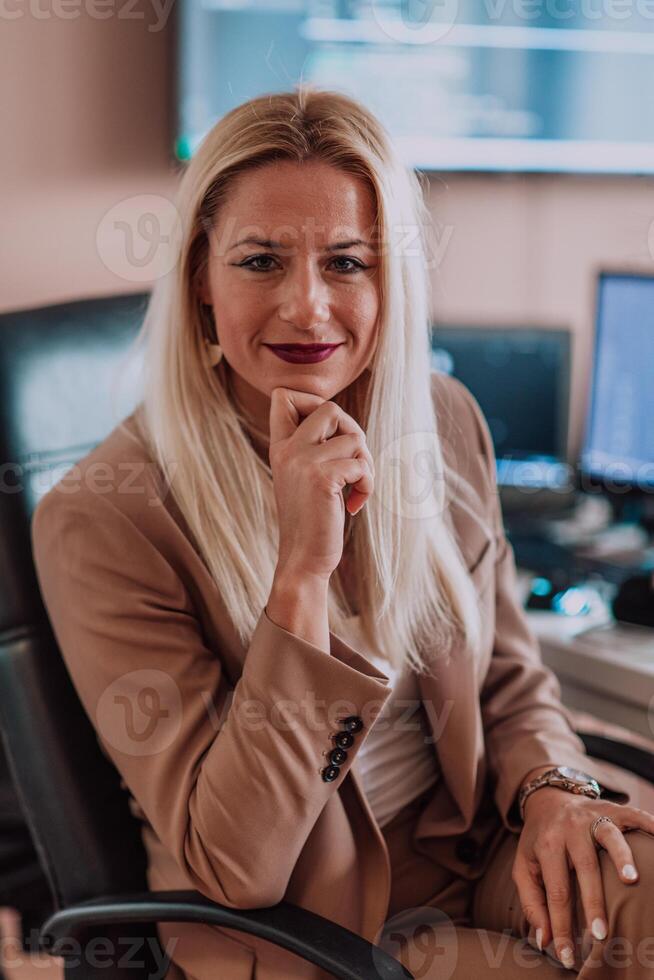 A businesswoman sitting in a programmer's office surrounded by computers, showing her expertise and dedication to technology. photo