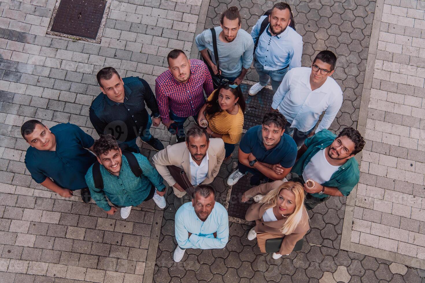 A top view photo of group of businessmen and colleagues standing together, looking towards the camera, symbolizing unity and teamwork.