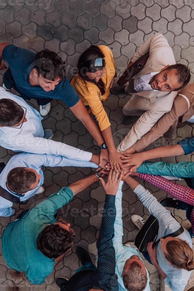 Top view photo of a group of business people and colleagues standing together holding hands, looking towards the camera, symbolizing unity and teamwork.