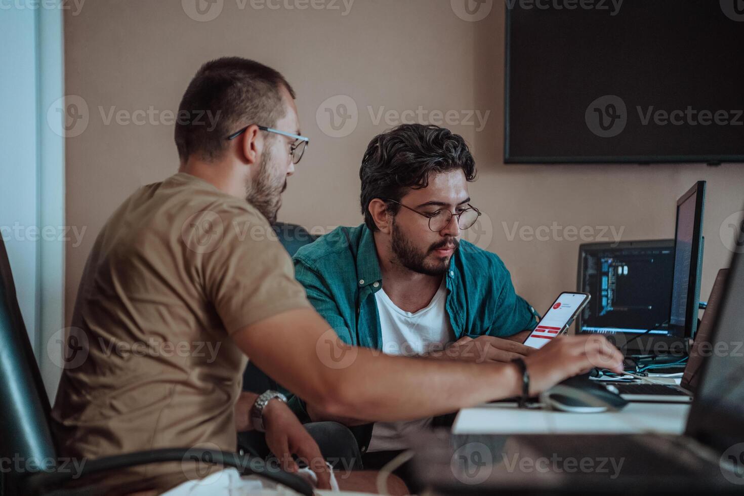 Programmers engrossed in deep collaboration, diligently working together to solve complex problems and develop innovative mobile applications with seamless functionality. photo