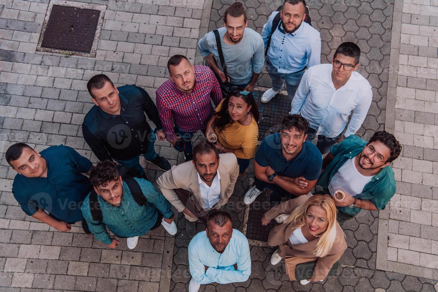A top view photo of group of businessmen and colleagues standing together, looking towards the camera, symbolizing unity and teamwork.