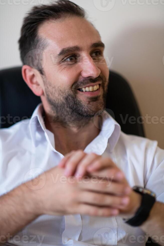 A businessman talking on his smartphone while seated in an office, showcasing his professional demeanor and active communication. photo
