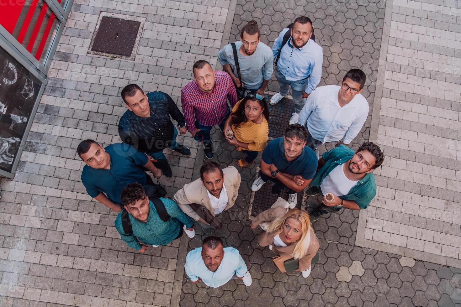 A top view photo of group of businessmen and colleagues standing together, looking towards the camera, symbolizing unity and teamwork.