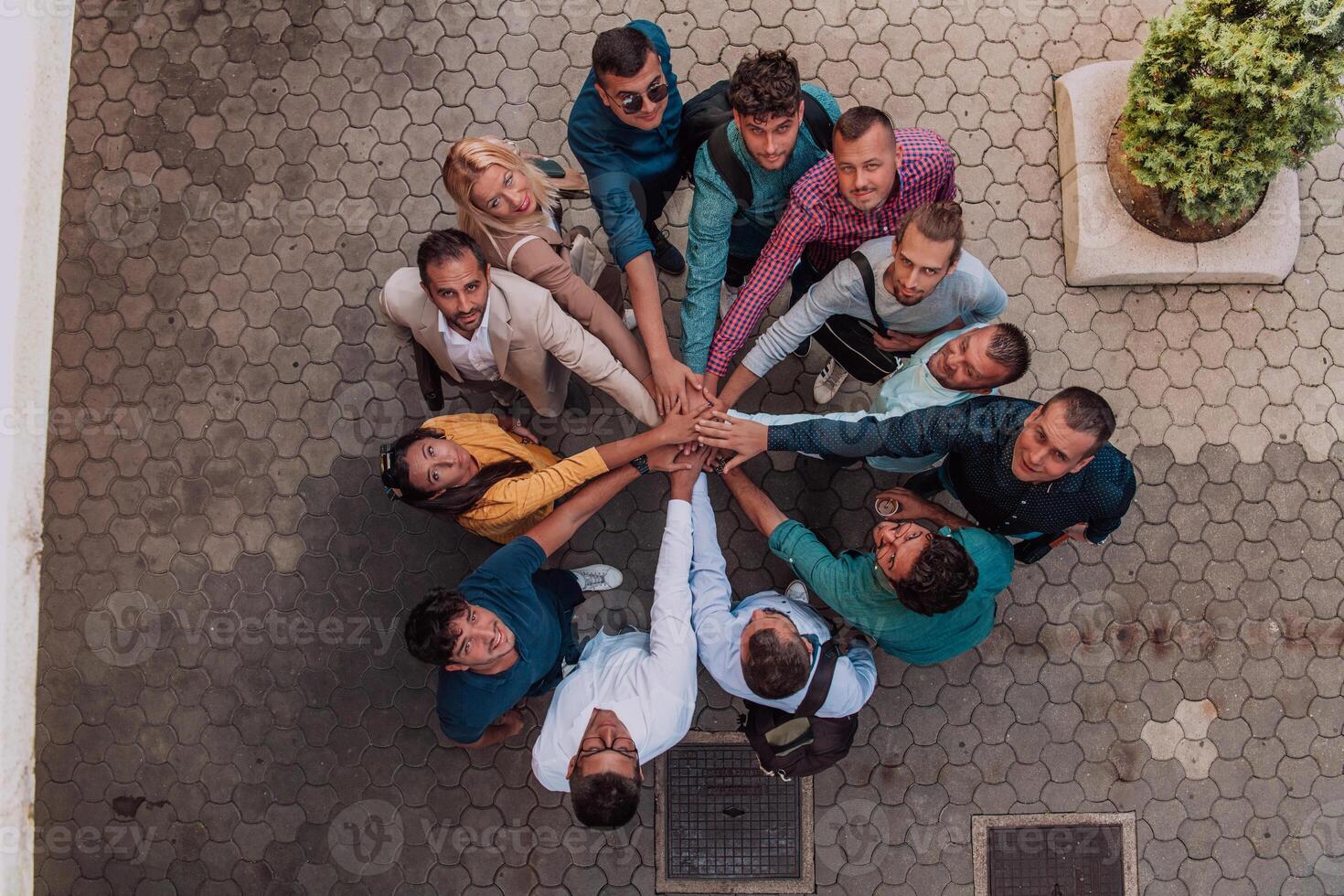 Top view photo of a group of business people and colleagues standing together holding hands, looking towards the camera, symbolizing unity and teamwork.