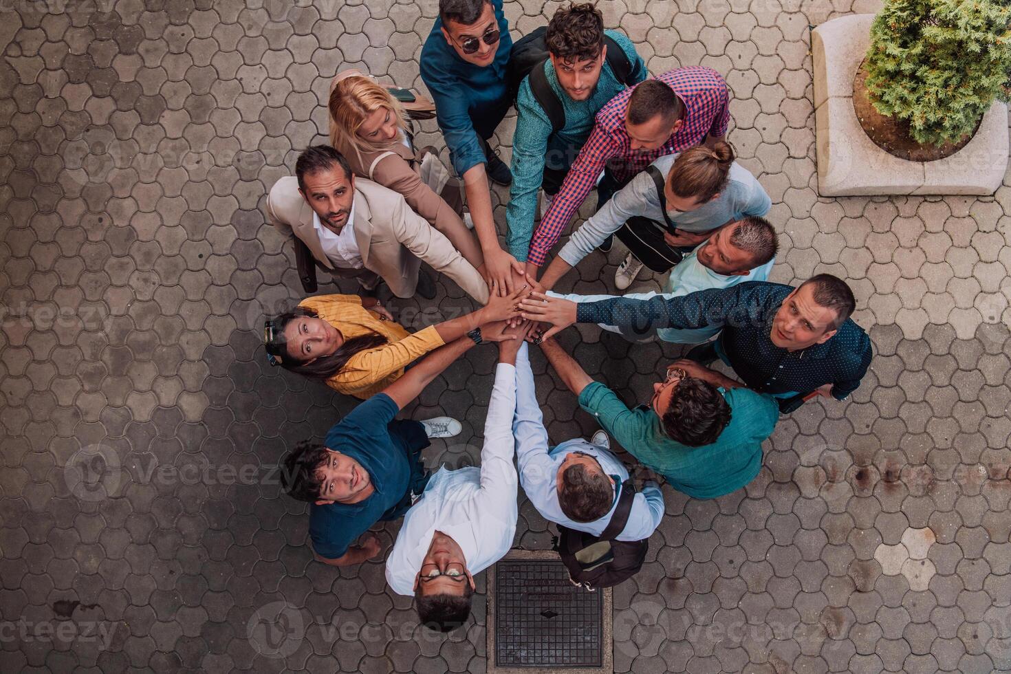 Top view photo of a group of business people and colleagues standing together holding hands, looking towards the camera, symbolizing unity and teamwork.