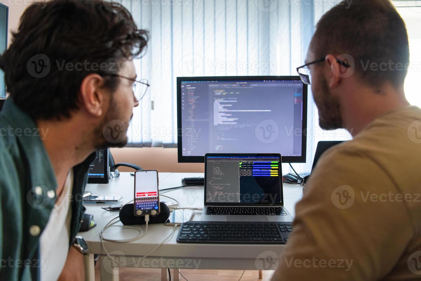 Programmers engrossed in deep collaboration, diligently working together to solve complex problems and develop innovative mobile applications with seamless functionality. photo