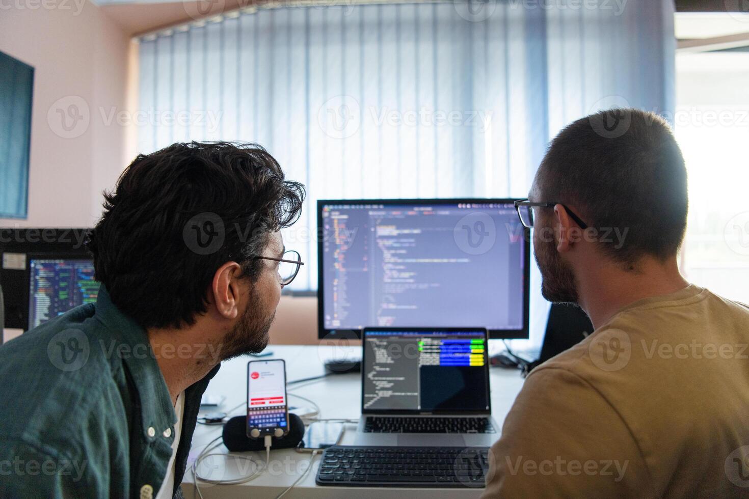 Programmers engrossed in deep collaboration, diligently working together to solve complex problems and develop innovative mobile applications with seamless functionality. photo