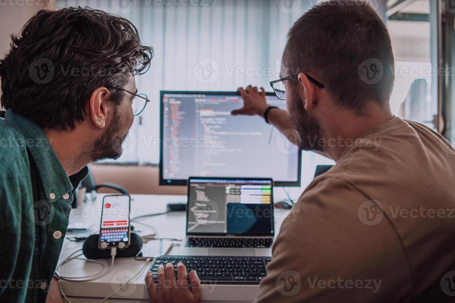 Programmers engrossed in deep collaboration, diligently working together to solve complex problems and develop innovative mobile applications with seamless functionality. photo
