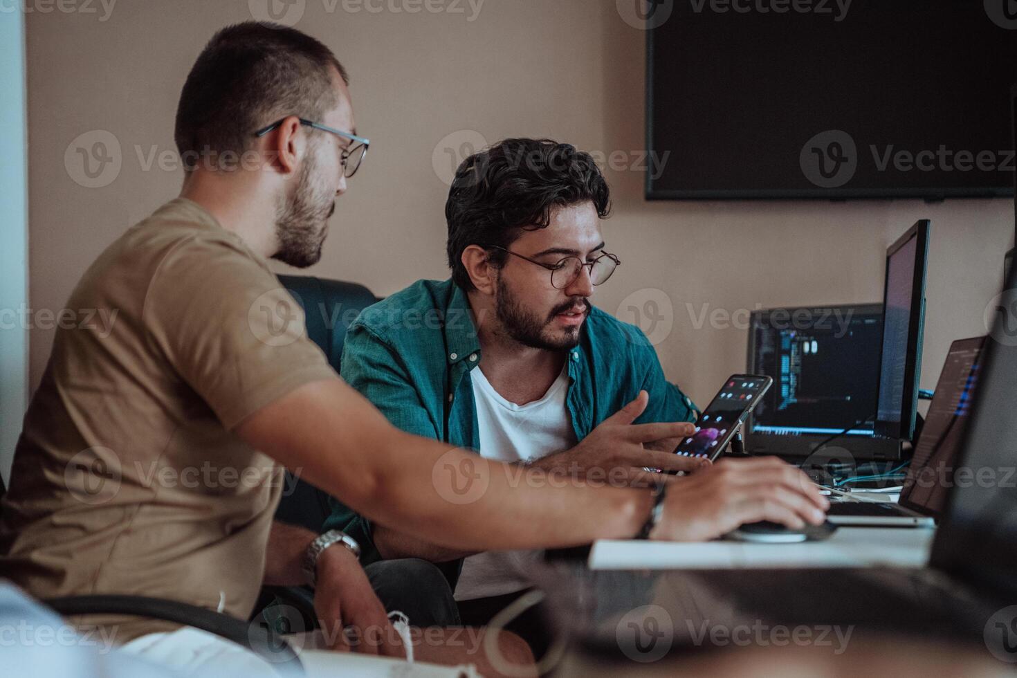 Programmers engrossed in deep collaboration, diligently working together to solve complex problems and develop innovative mobile applications with seamless functionality. photo