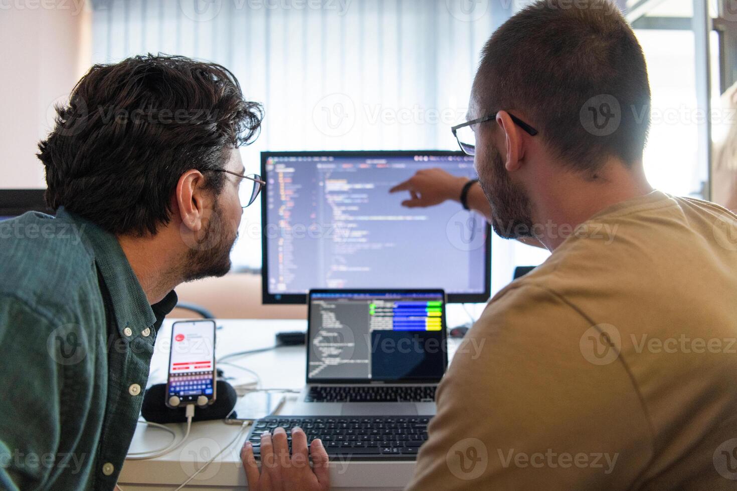 Programmers engrossed in deep collaboration, diligently working together to solve complex problems and develop innovative mobile applications with seamless functionality. photo