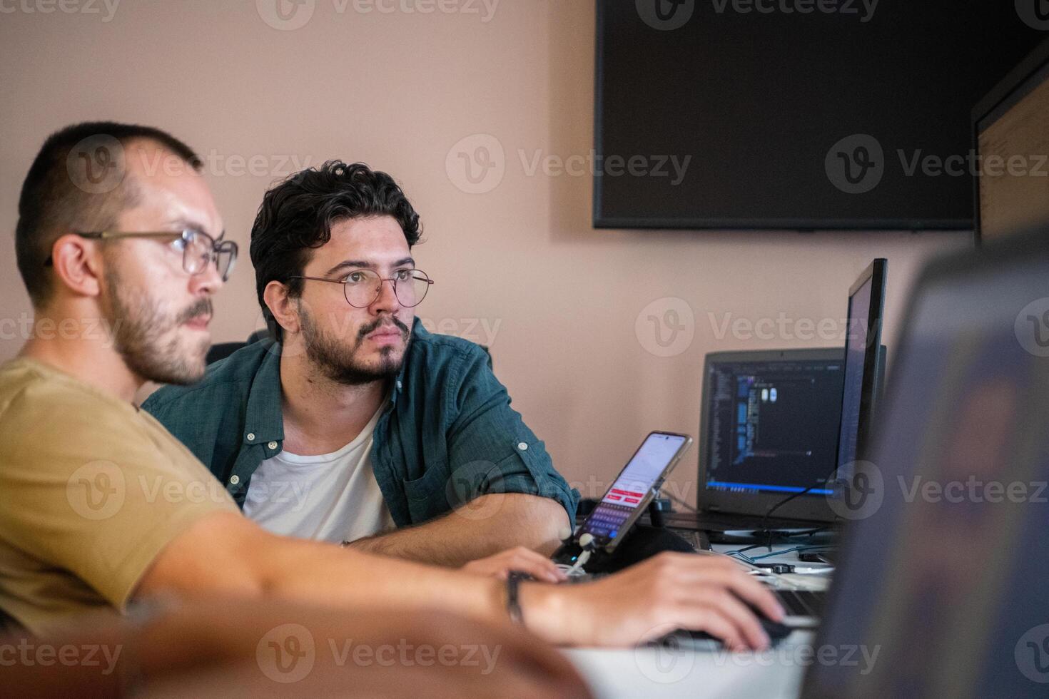 Programmers engrossed in deep collaboration, diligently working together to solve complex problems and develop innovative mobile applications with seamless functionality. photo