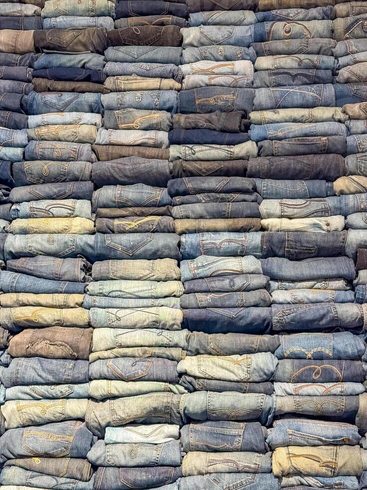 Stacked folded jeans in various shade of blue, creating a textured denim pattern. High quality photo