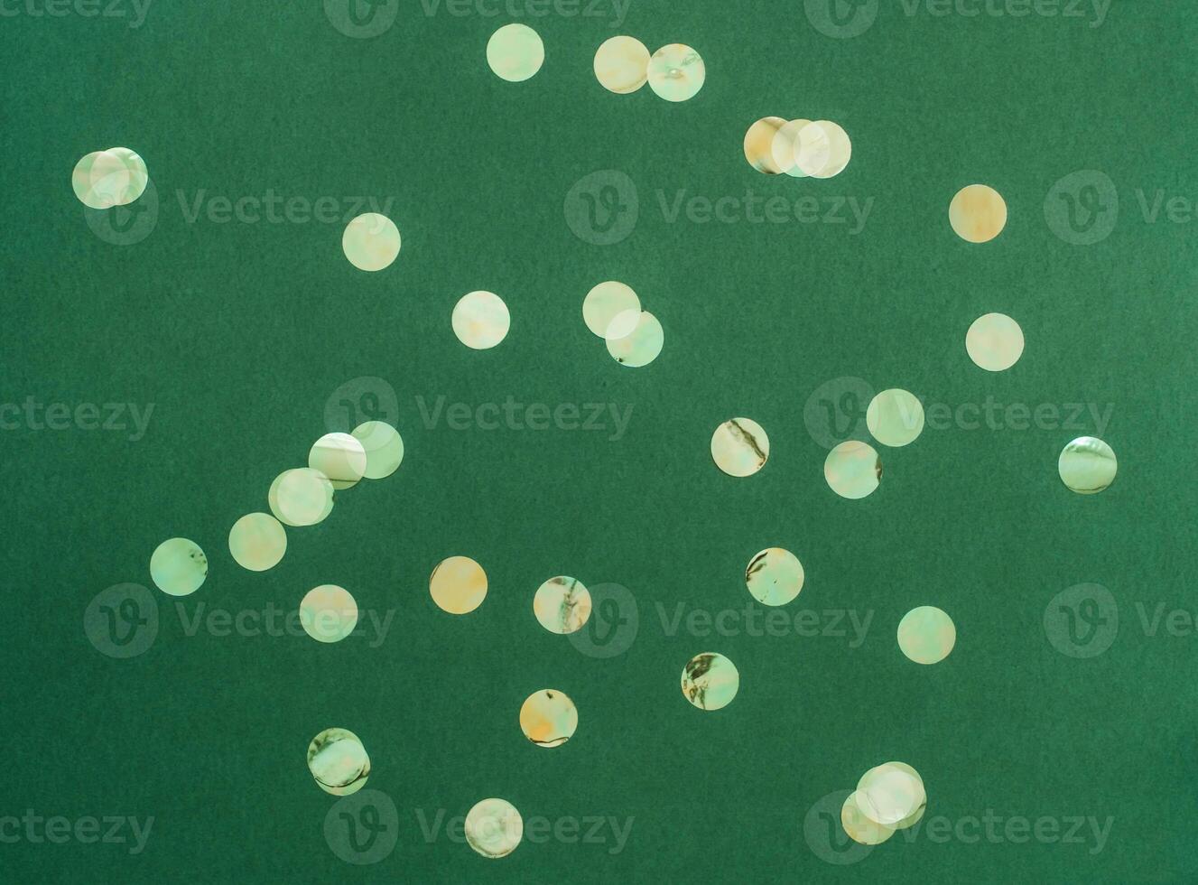 Festive flat-lay arrangement featuring green glittery baubles scattered across green background photo