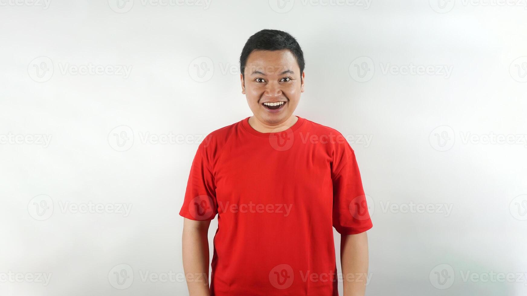 A young Indonesian man wearing a red t-shirt with a surprised face facing forward photo