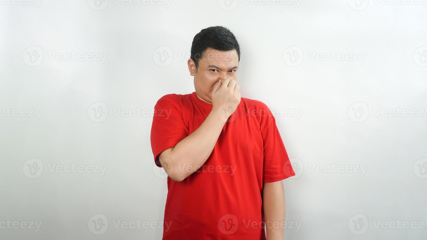A young Indonesian man wearing a red t-shirt with a disgusted face facing forward photo