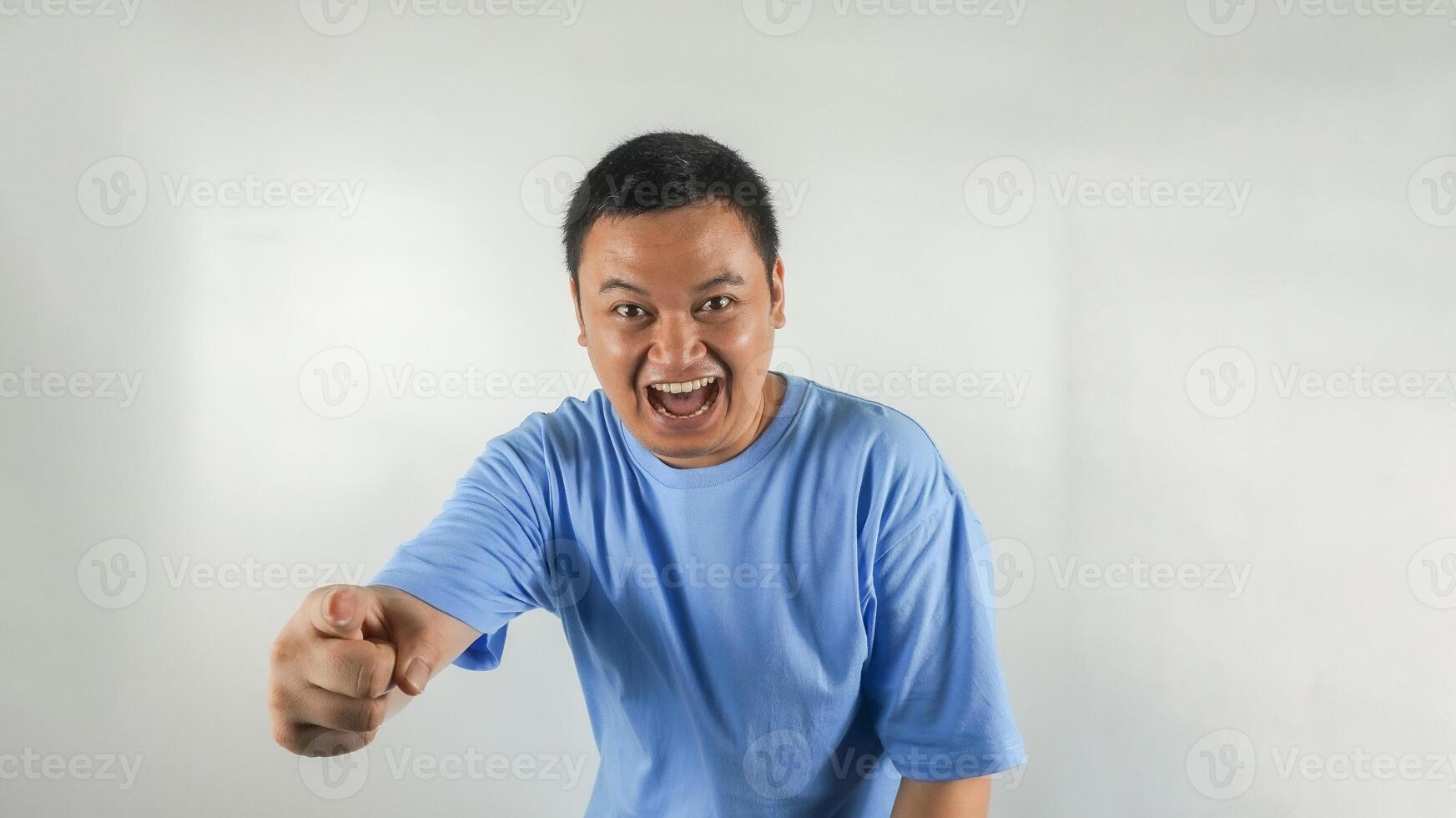 A young Indonesian man wearing a blue t-shirt is laughing facing forward photo