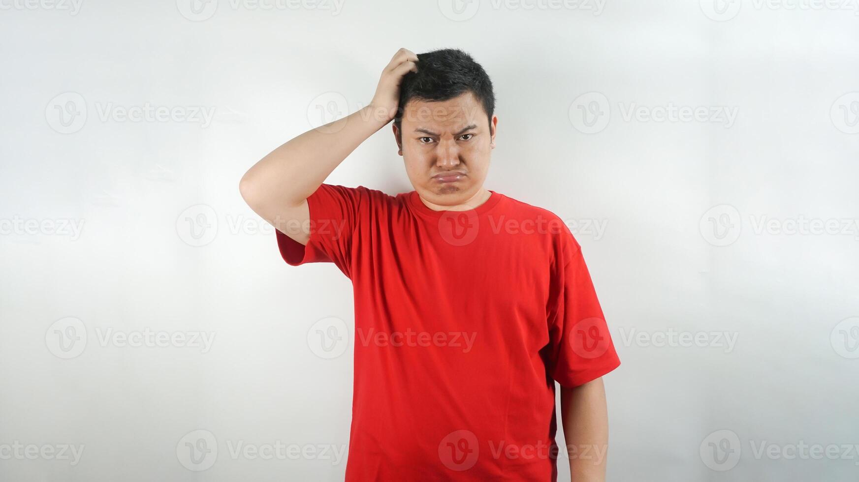 A young Indonesian man wearing a red t-shirt with a frown facing forward photo