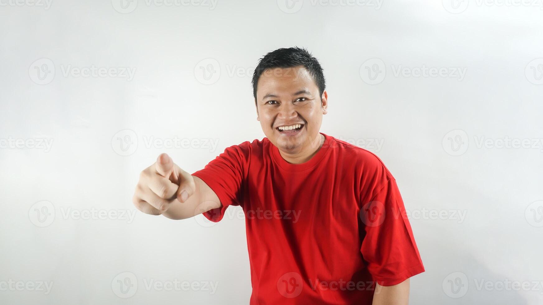 A young Indonesian man wearing a red t-shirt is laughing facing forward photo