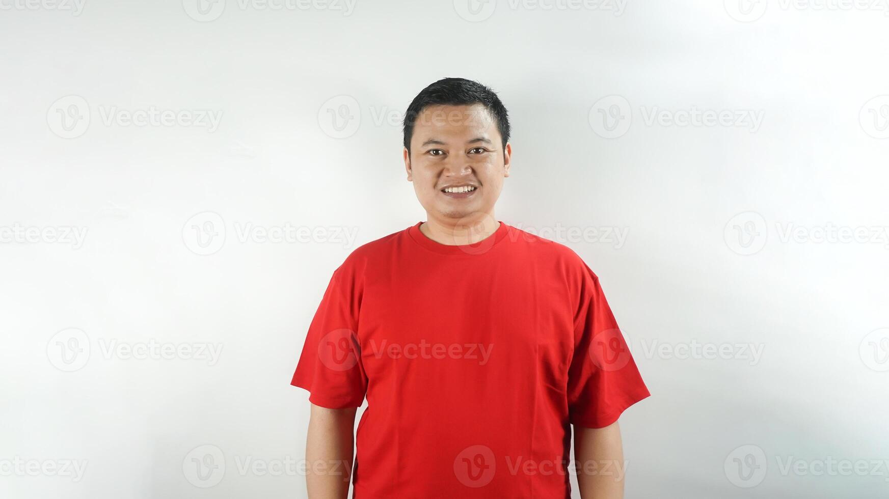 A young Indonesian man wearing a red t-shirt with a smiling face facing forward photo