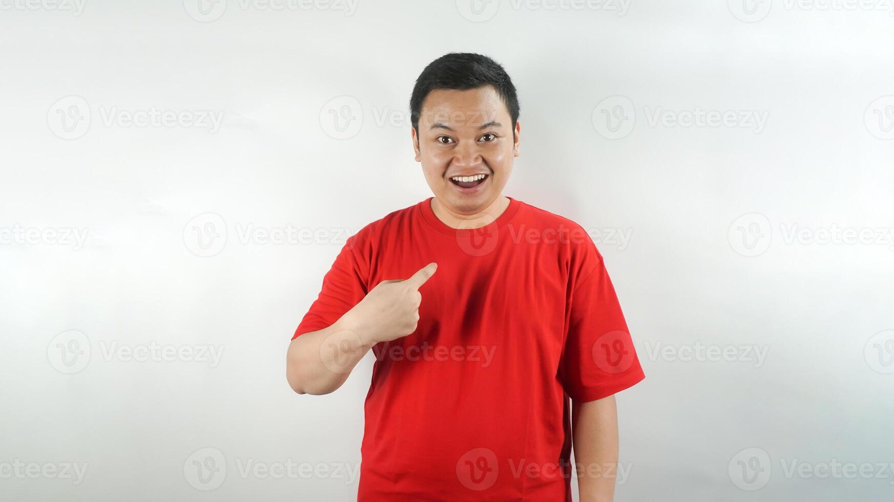 A young Indonesian man wearing a red t-shirt with a surprised face facing forward photo