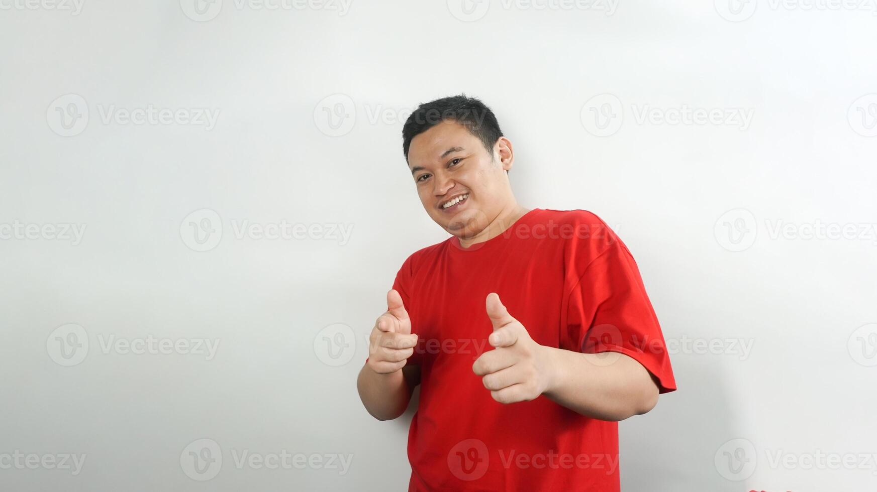 A young Indonesian man wearing a red t-shirt with a happy face pointing photo