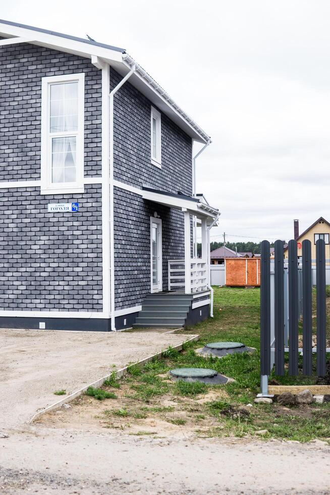 The house is made of timber lined with gray brick. A house with a veranda. The concept of living outside the city. photo