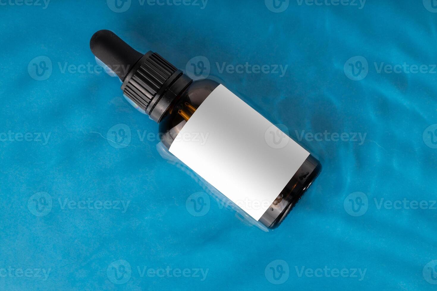 Amber Dropper Bottle on Blue Water Surface with Blank Label photo