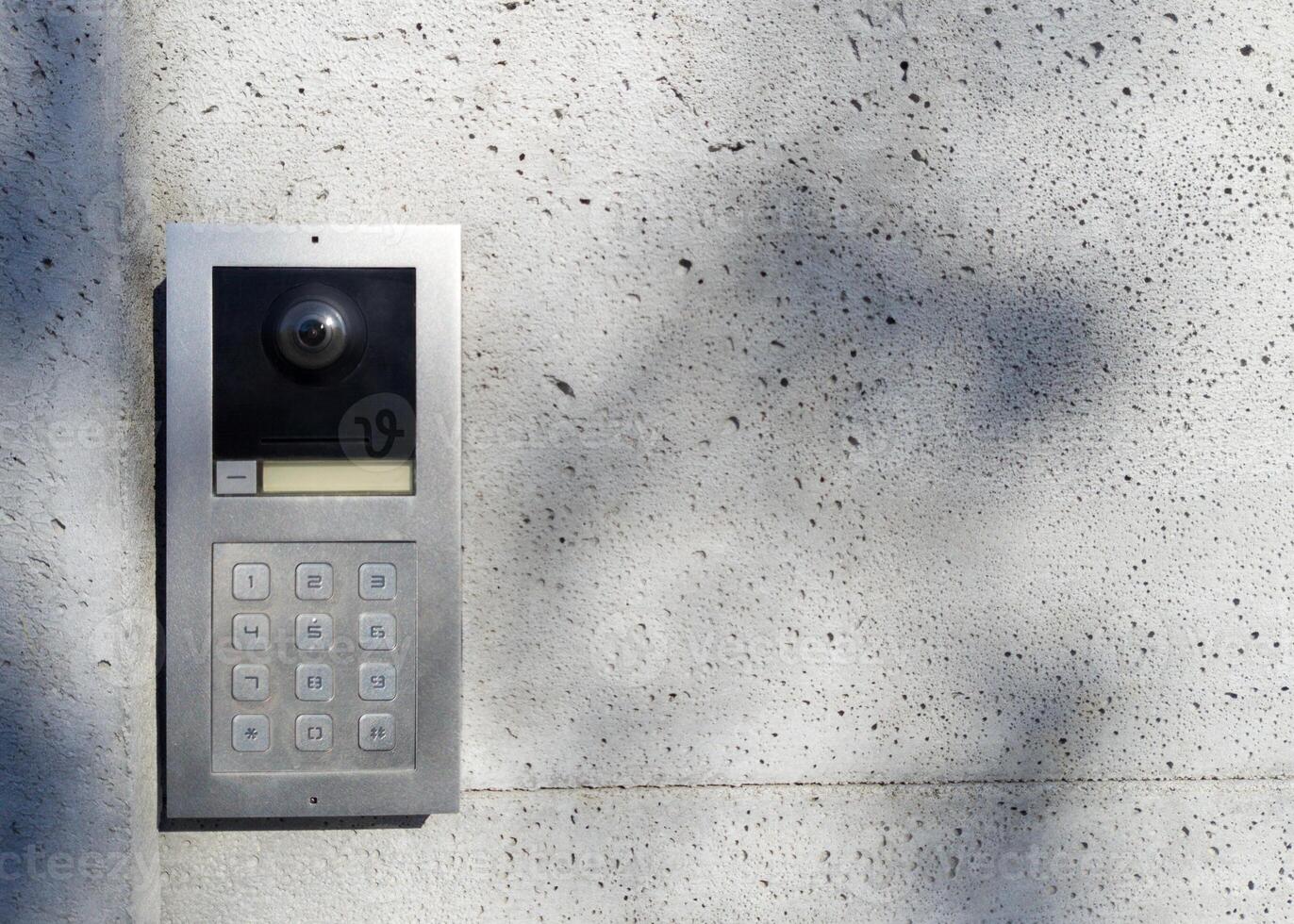 Metal intercom with keypad on concrete wall photo