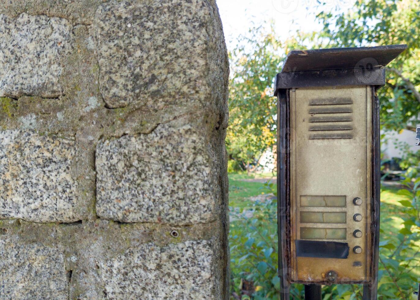 Weathered intercom on stone wall outdoors photo