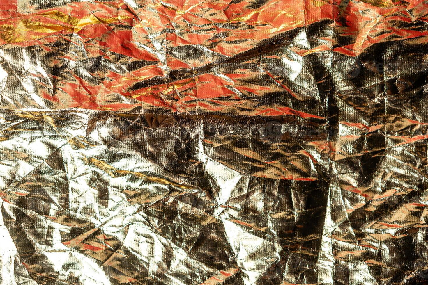 Crumpled Metallic Foil Texture with Red and Gold Hues photo
