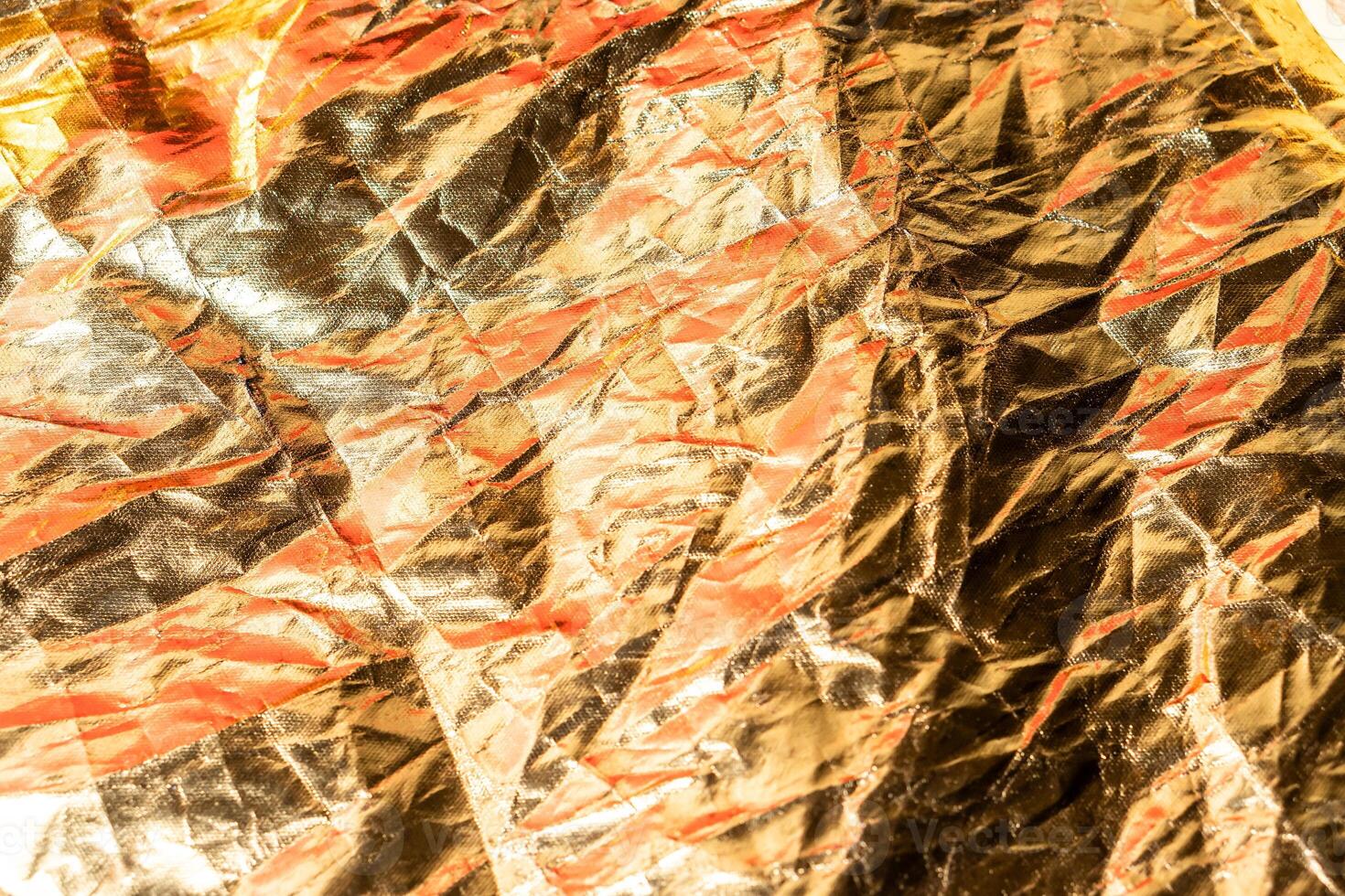 Crumpled Metallic Foil Texture with Red and Gold Hues photo