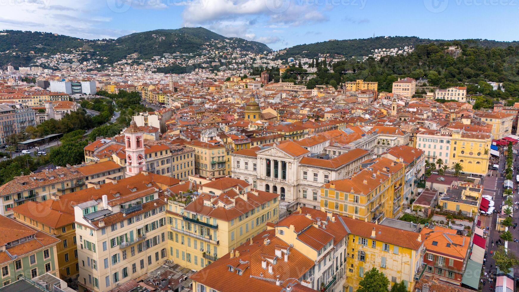 Aerial view of Nice, France, showcasing the vibrant Old Town with its colorful buildings and iconic terracotta rooftops. Surrounded by green hills photo