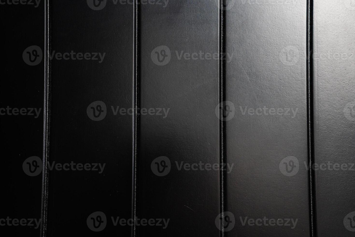 Close-up of smooth black wooden panels arranged in parallel lines under soft light creating an elegant interior ambiance photo