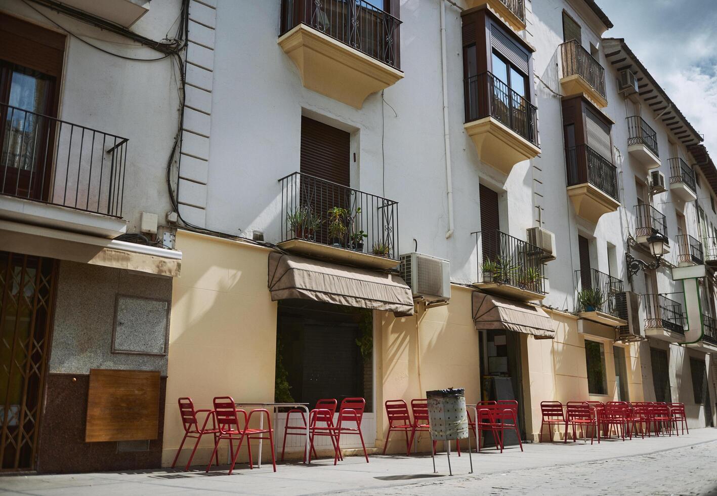 Charming city street with outdoor cafe and red chairs photo