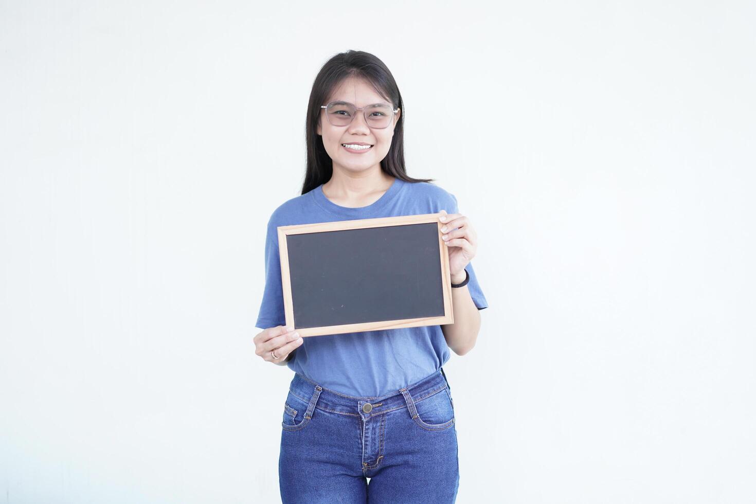 Beautiful Asian woman smiles while holding a blank blackboard, ready for promotion against a white background photo