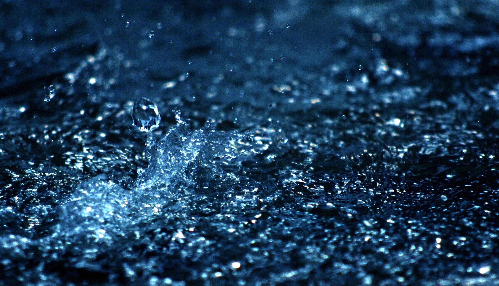 Water drops levitating in the air in dark. Splashing water fly in the air. Part of the drops is in focus, part - out of the focus. photo