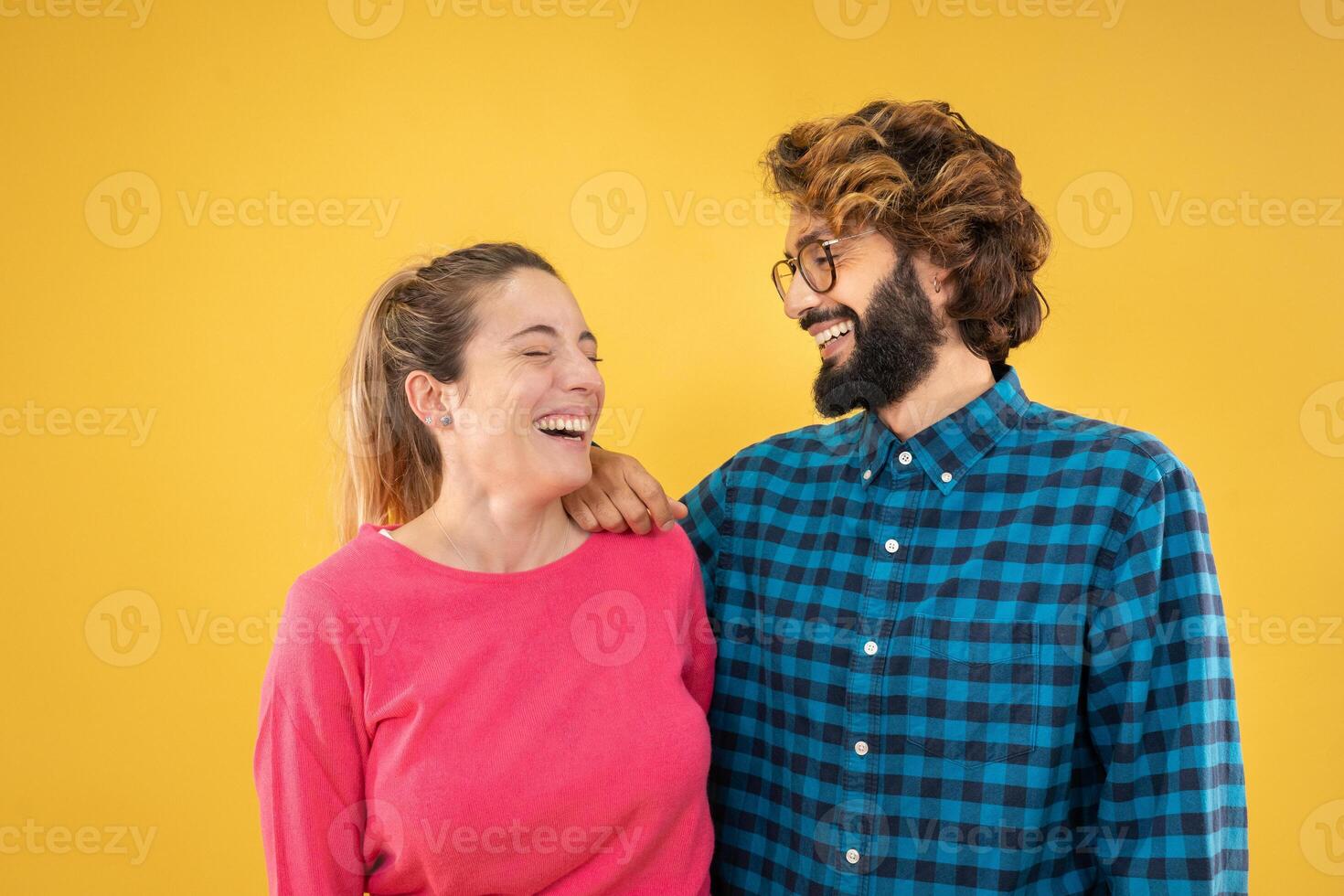 Young couple of man and woman laughing, smiling, happy isolated on yellow color background. photo
