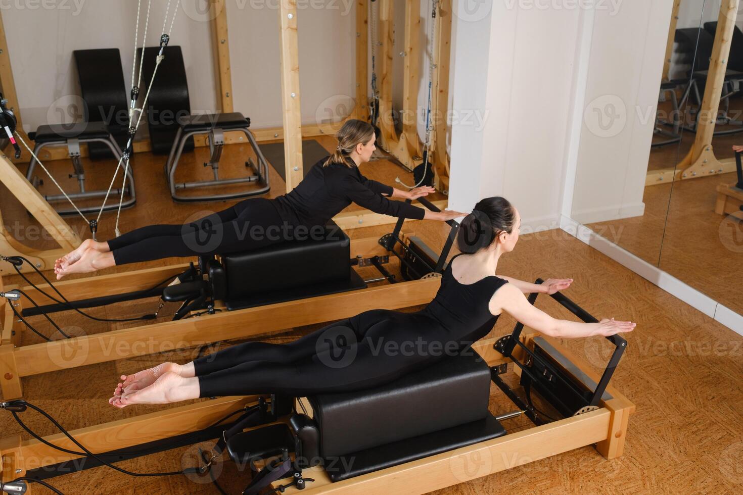Two women balance on a pilates reformer machine in the gym photo