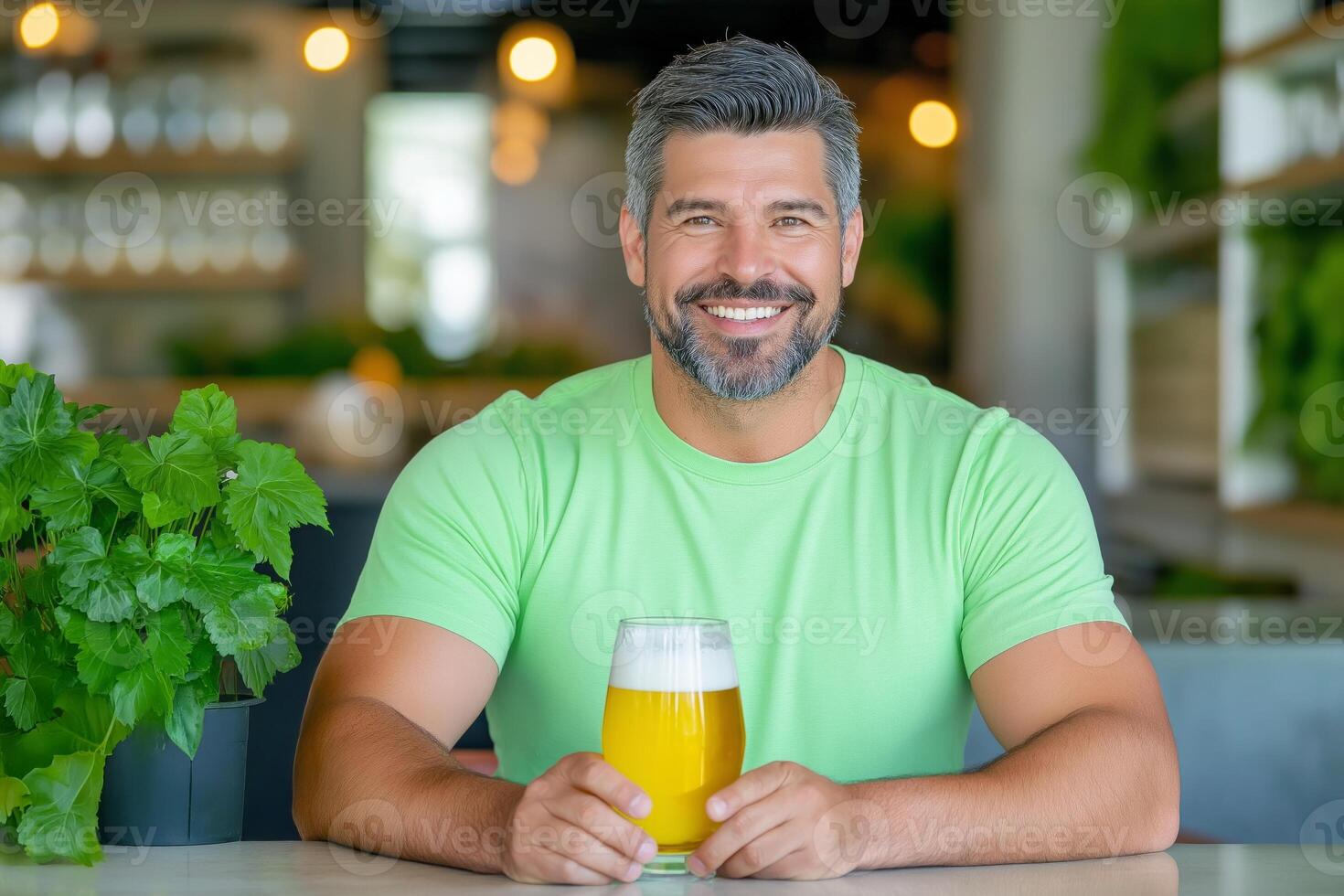 Cheerful man in a green shirt enjoys a refreshing drink in a cozy cafe setting during the afternoon photo