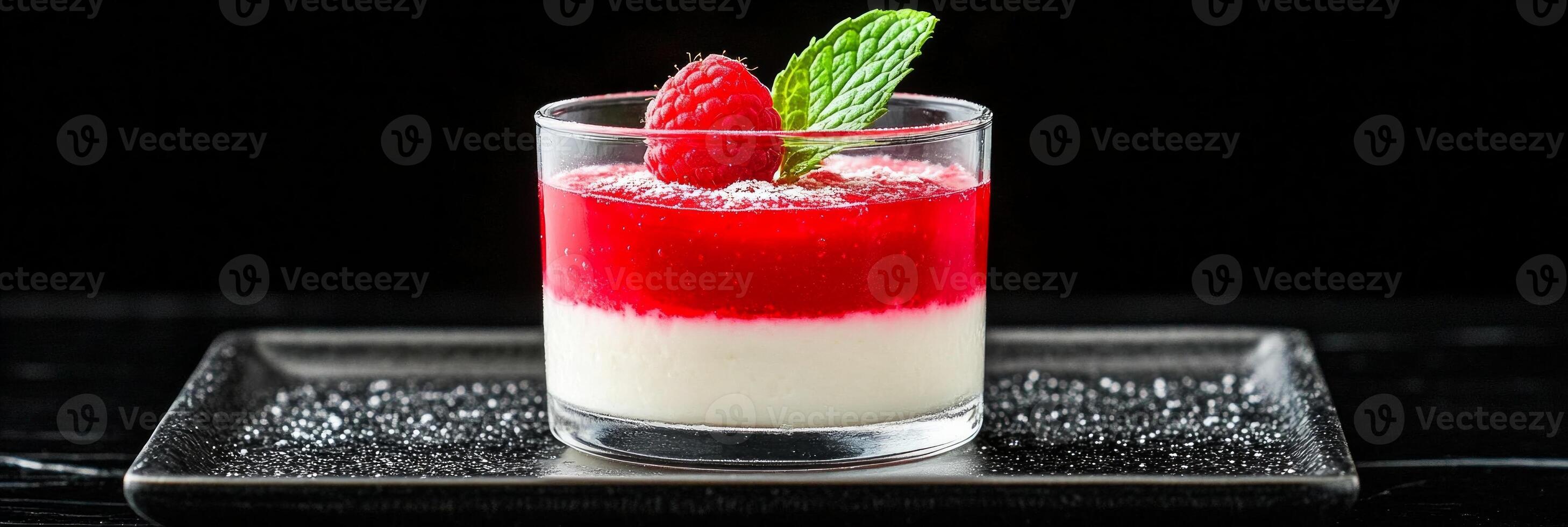 Elegant raspberry panna cotta in a glass served on a black plate, showcasing rich textures and vibrant colors photo