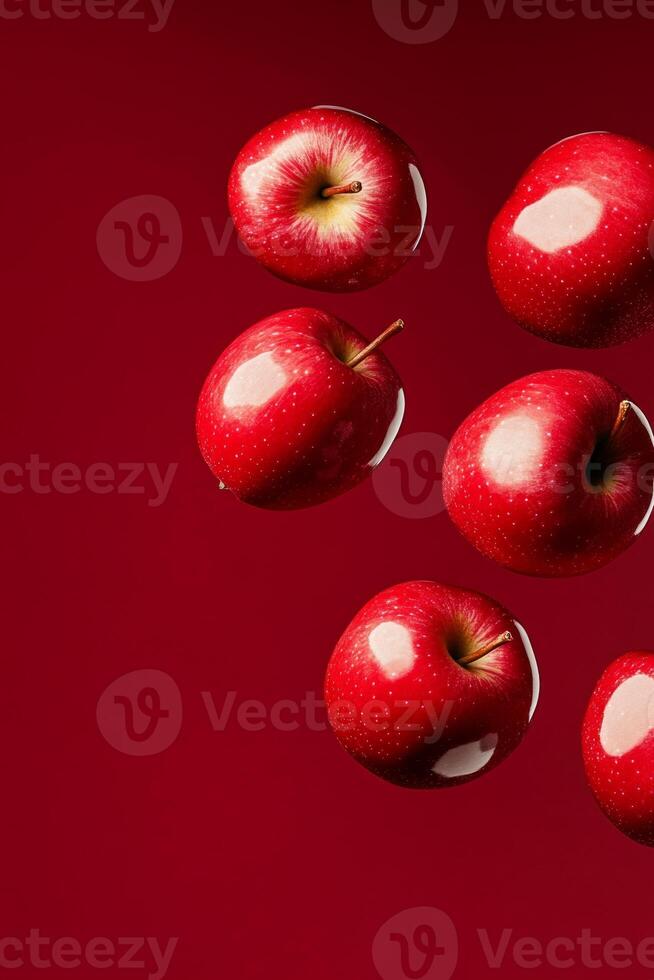 Bright red apples bouncing in mid-air against a vibrant red background showcasing their glossy texture photo