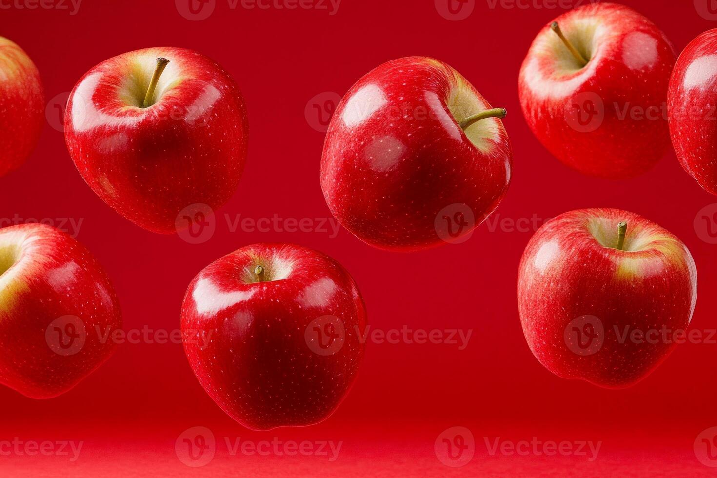 Bright red apples bouncing mid-air against a rich red backdrop showcasing their vibrant color and shine photo