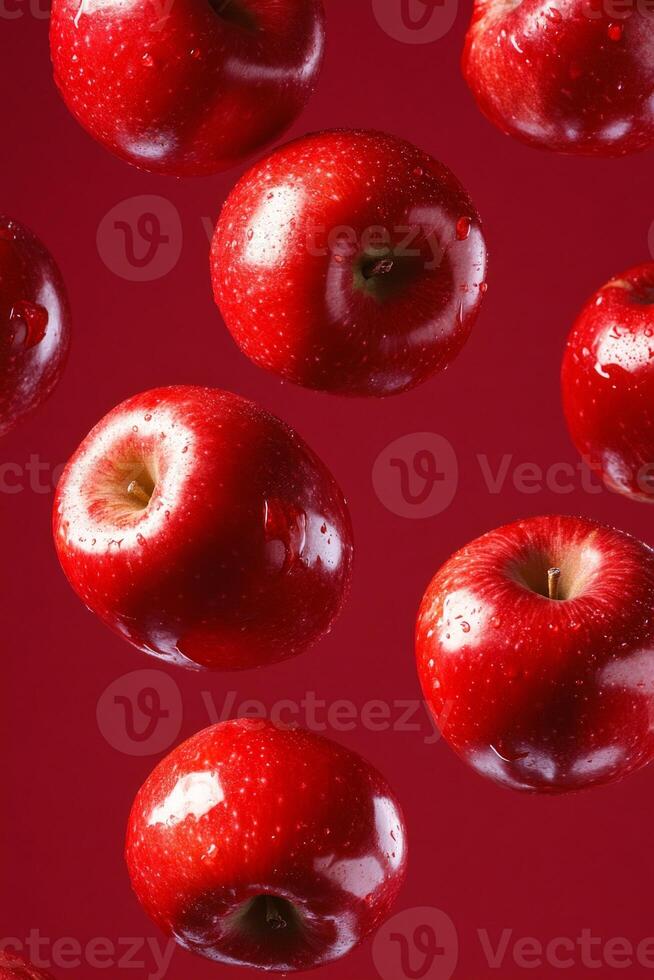 Bright red apples float mid-air against a deep red backdrop, showcasing their vivid color and glossy texture photo