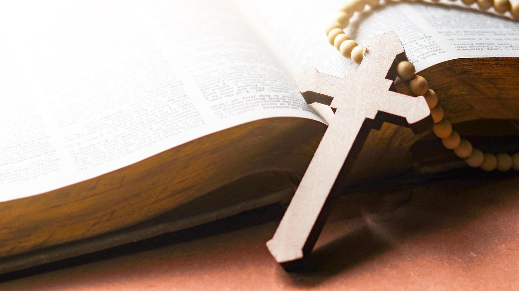 Brown wooden cross on an old open book symbolizing the spread of Jesus Christs love among Christians reflecting faith devotion and the importance of Christian teachings. photo