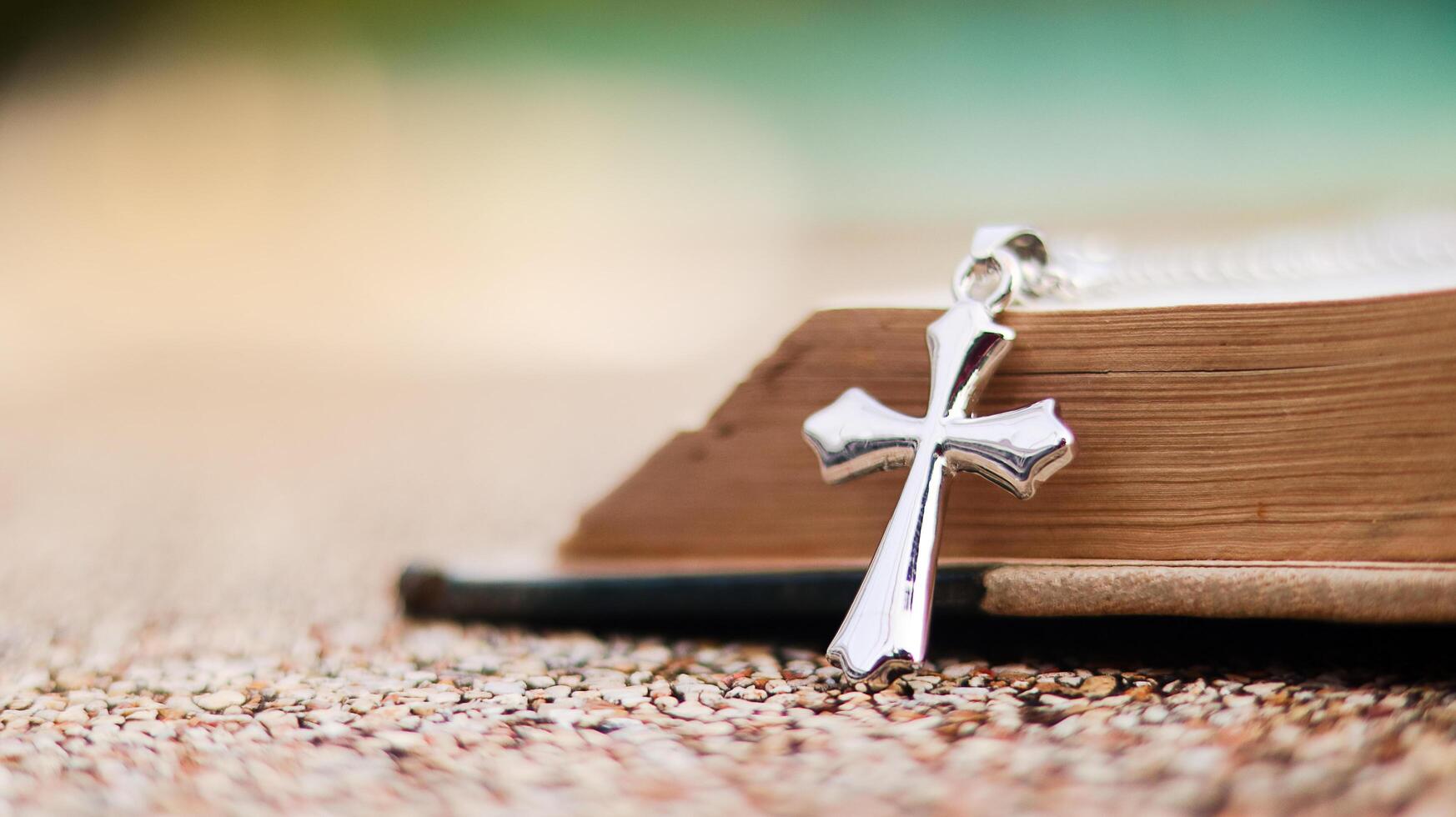 Shiny metal cross leaning against an old open book symbolizing the spread of Jesus Christs love among Christians reflecting faith devotion and the importance of Christian teachings. photo