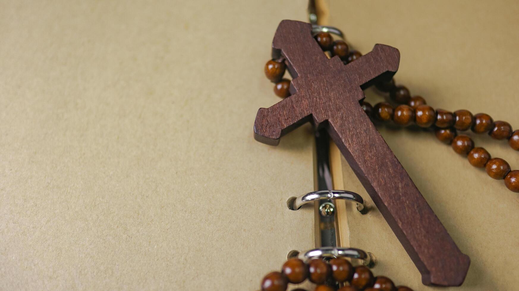 Dark red wooden cross leaning against an old open book symbolizing the spread of Jesus Christs love among Christians reflecting faith devotion and the importance of Christian teachings. photo