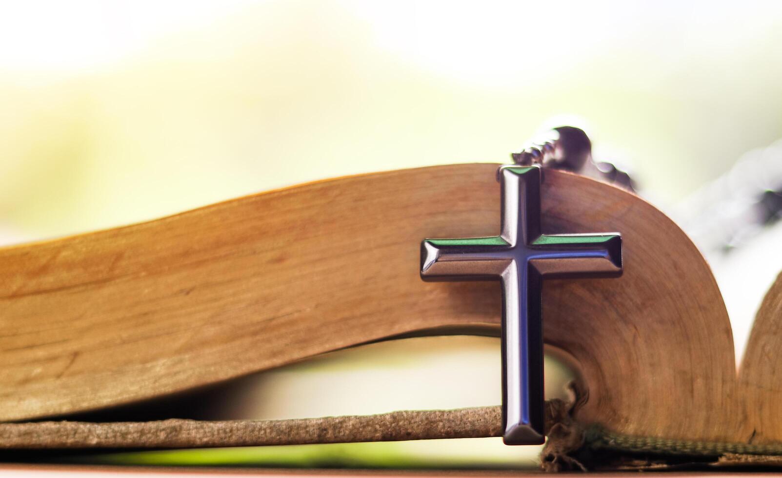 Dark metal cross on an old open book symbolizing the spread of Jesus Christs love among Christians reflecting faith devotion and the importance of Christian teachings. photo